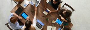 Top view of a diverse team collaborating in an office setting with laptops and tablets, promoting cooperation.